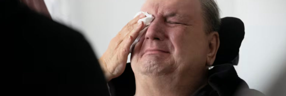 Normand Meunier’s partner wipes his tears during an interview