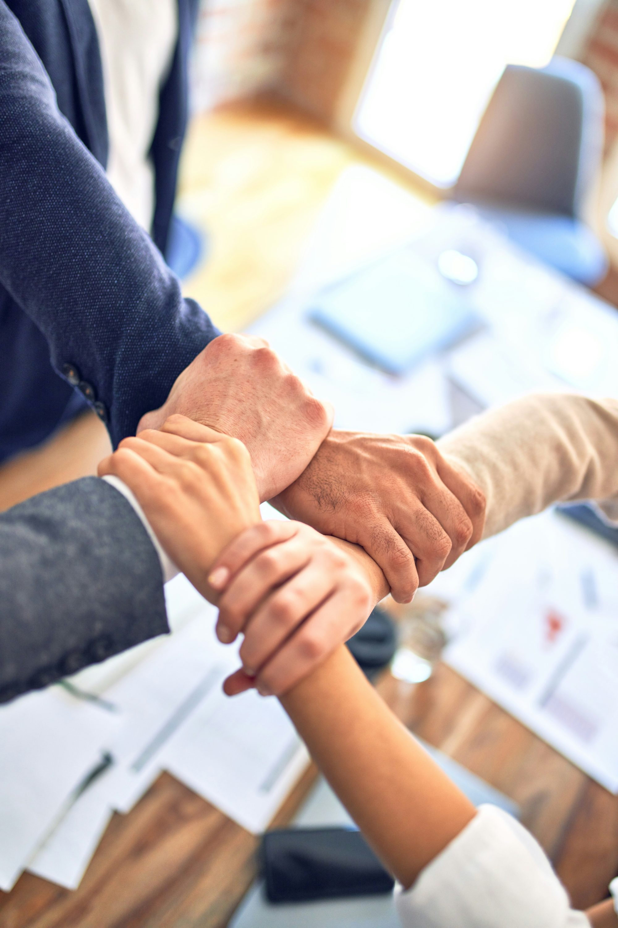 Four people with interlocked hands, symbolizing working together for a greater cause