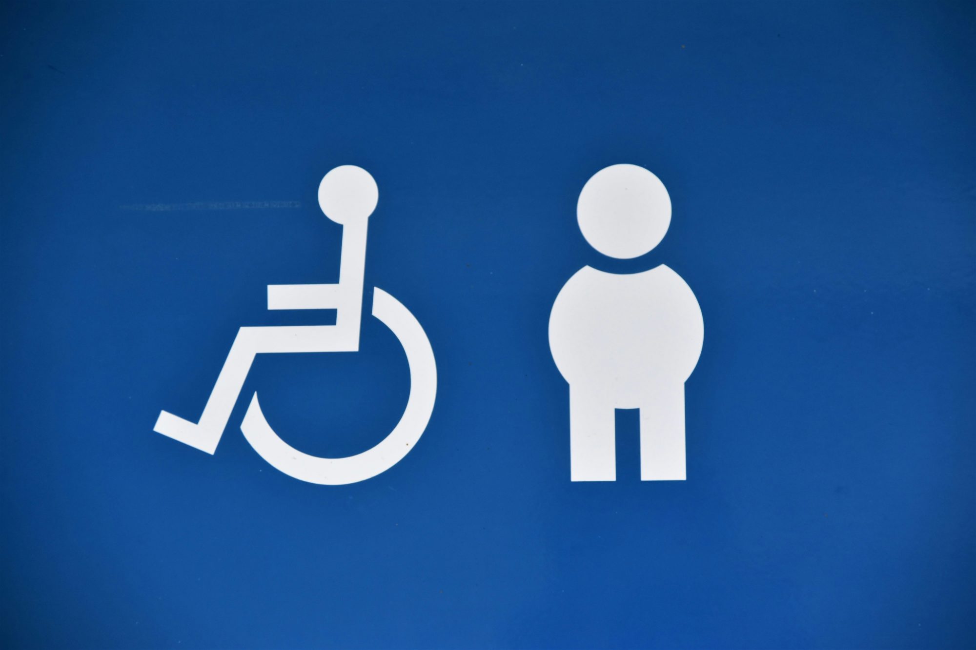 White text on blue background showing a disability emoji facing away from an emoji of a standing person